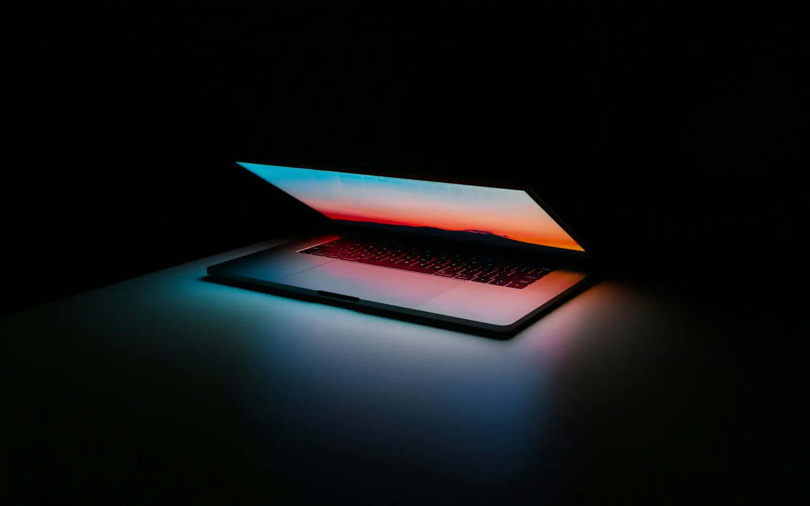 A laptop opening with a glowing screen in the dark